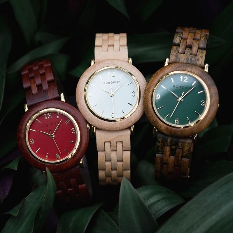 Montre Bois Femme au Cadran Épuré et Coloris Naturels les 3 couleurs rouge, blanche et verte sur fond végétal