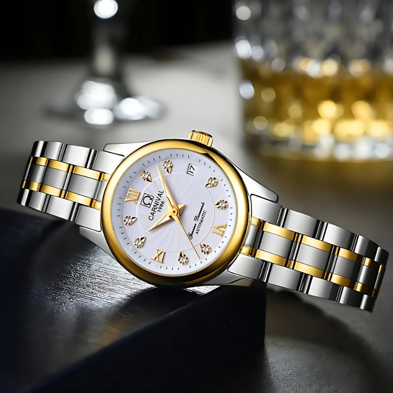 Montre Automatique Femme Acier Bicolore Cadran Cristal posée sur une table avec un verre en arrière plan