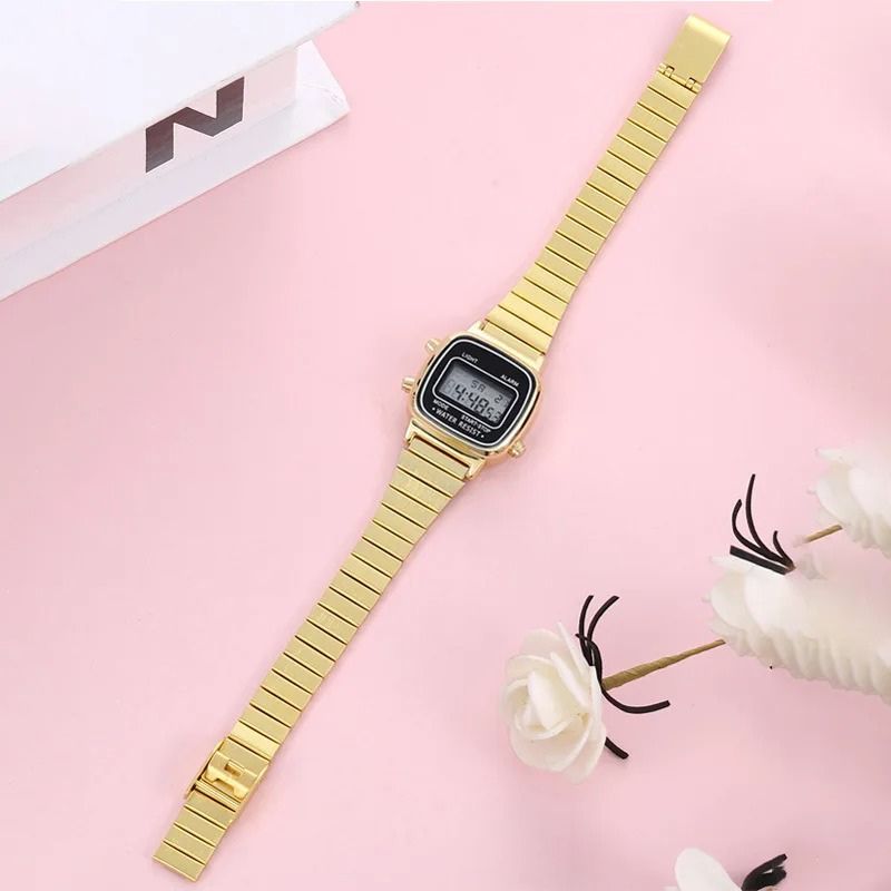Montre Digitale Femme au Design Carré Rétro couleur or, étendue sur un fond de couleur or