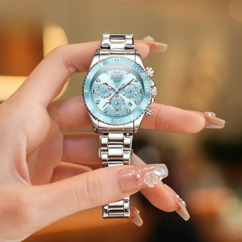Montre chronographe femme cadran bleu glacier et acier miroir portée dans la main d'une femme aux longs ongles