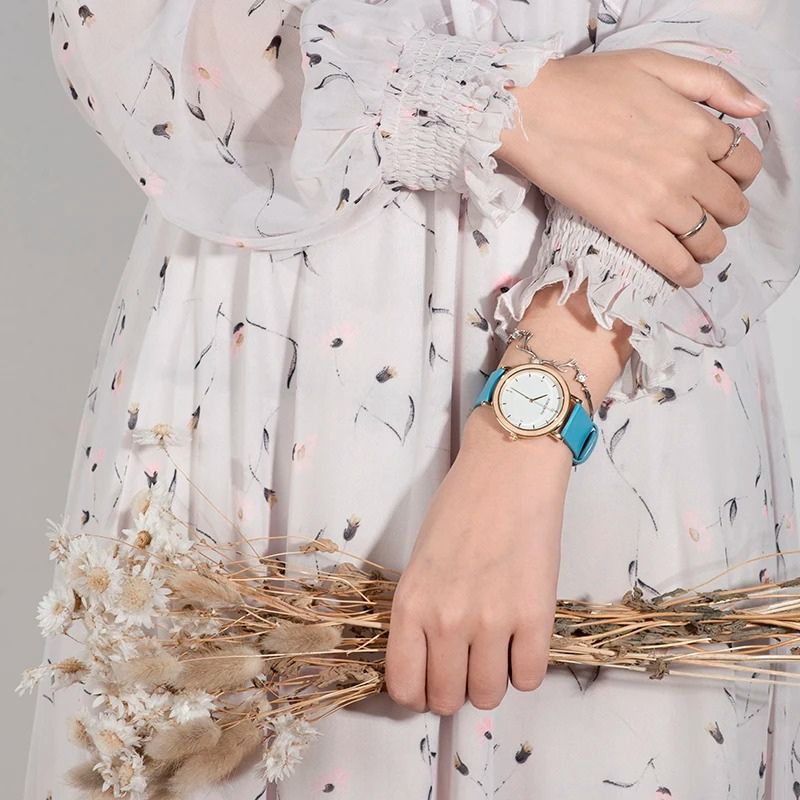 Montre Bois Femme Colorée au Cadran Minimaliste Doré couleur bleu portée au poignet d'une femme blanche