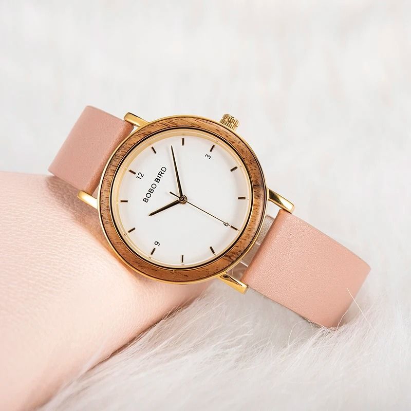Montre Bois Femme Colorée au Cadran Minimaliste Doré couleur rose posée sur un fond clair