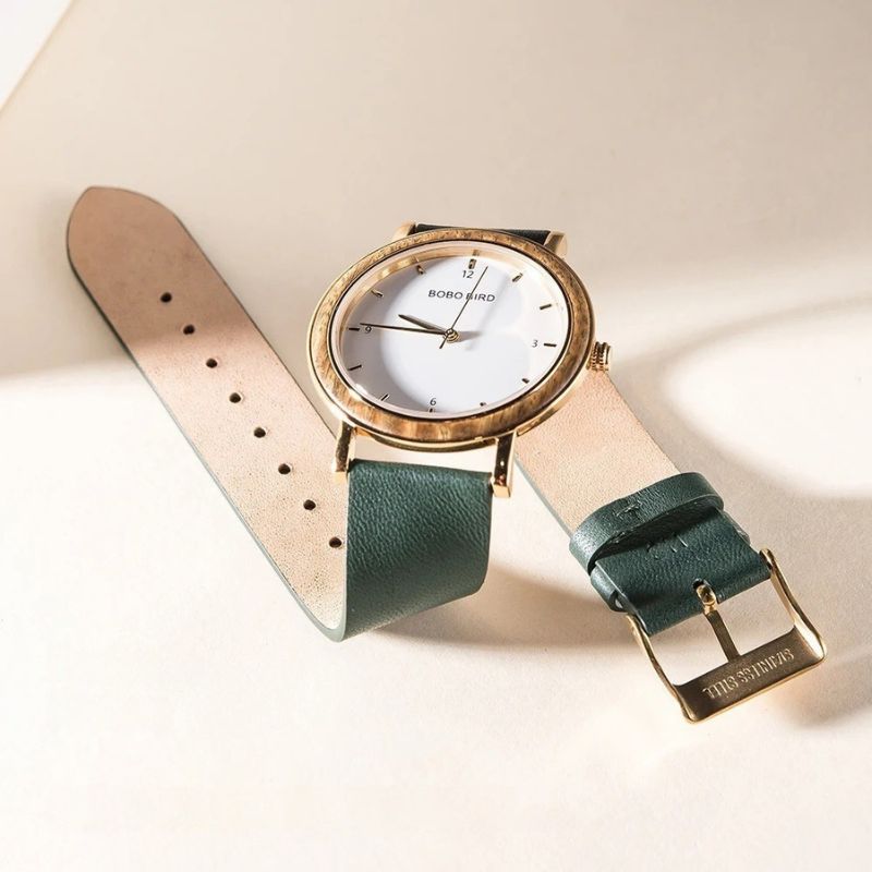 Montre Bois Femme Colorée au Cadran Minimaliste Doré couleur verte posée sur un fond clair