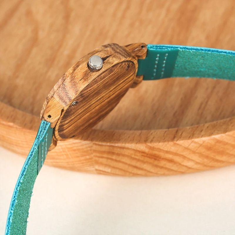 Montre Bois Femme au Cadran Turquoise Naturel de coté posée sur un décor en bois