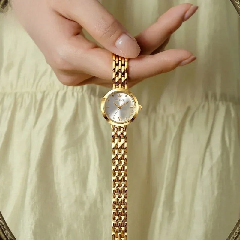 Montre Vintage de luxe pour Femme dorée tenue à la main, détails précis et éclat raffiné.