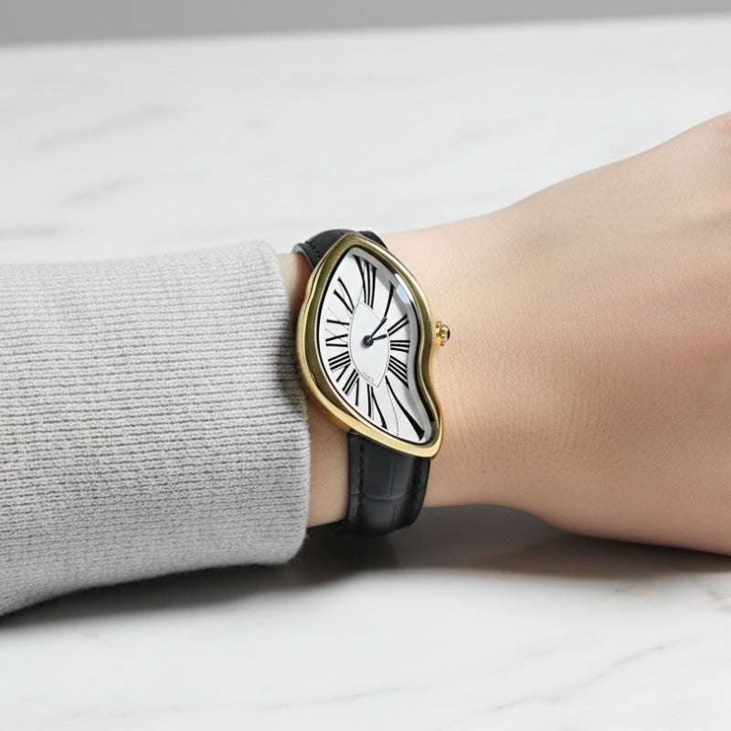 Montre Vintage pour Femme de forme irrégulière argentée portée au poignet, cadran à chiffres romains et bracelet noir en cuir.