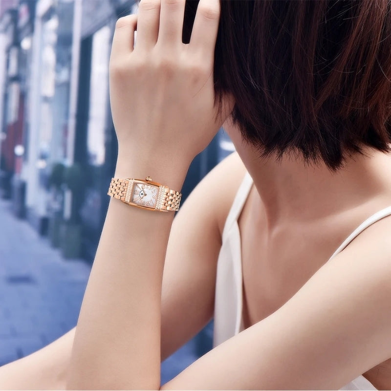 Montre Vintage pour Femme de forme rectangulaire or rose portée au poignet, cadran nacré lumineux et allure sophistiquée.