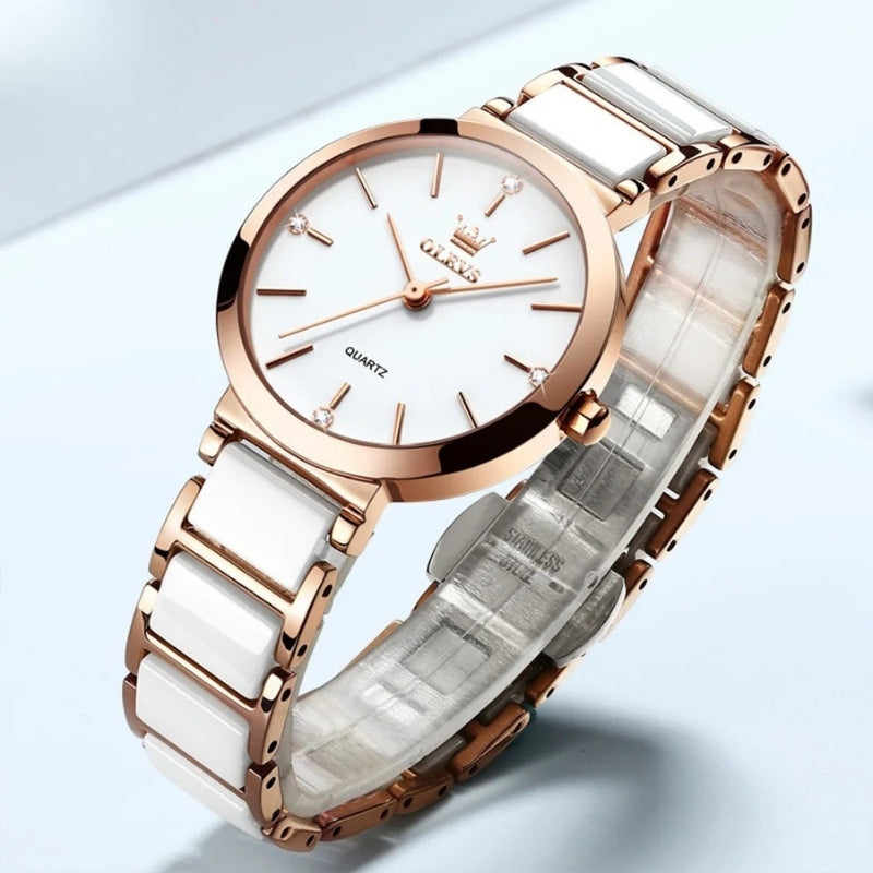 Montre Vintage pour Femme de forme ronde or rose et blanche posée sur fond clair, cadran lumineux et bracelet céramique raffiné.
