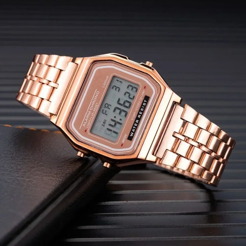 Montre Digitale Femme au Bracelet Métal Finition Brillante couleur or rose posée sur un décor sombre