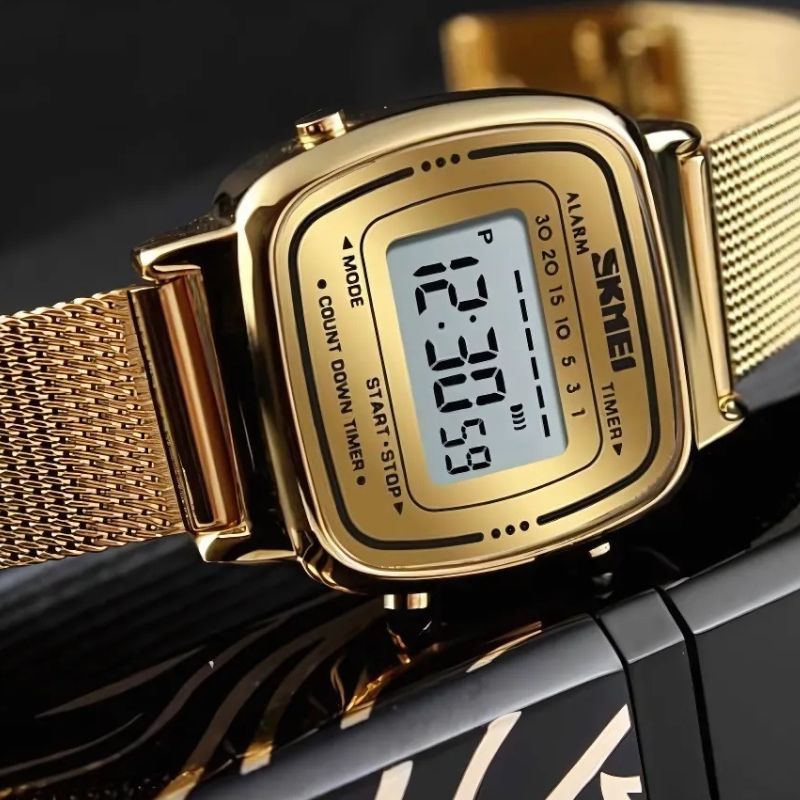 Montre Digitale Femme au Cadran Carré Métallisé couleur or posé sur un fond décoratif Image