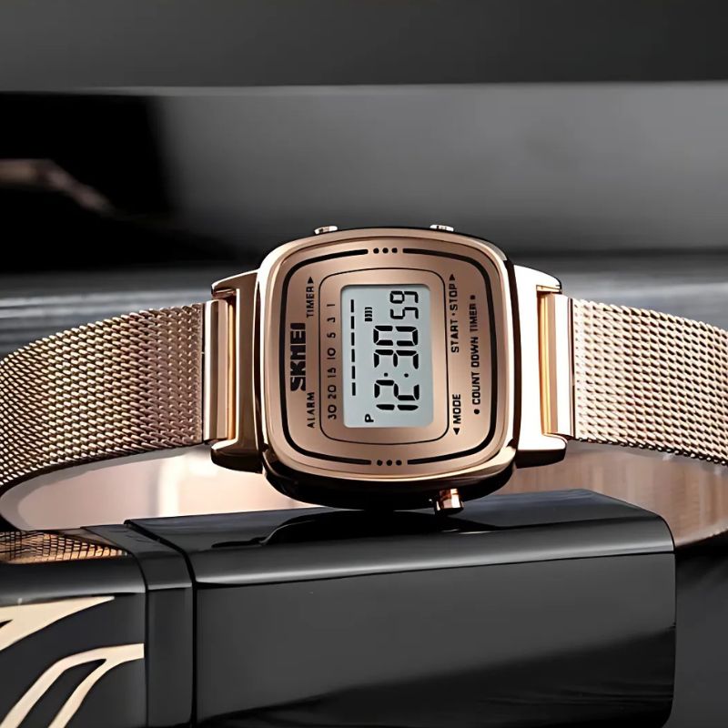 Montre Digitale Femme au Cadran Carré Métallisé couleur or rose posée sur un fond décoratif