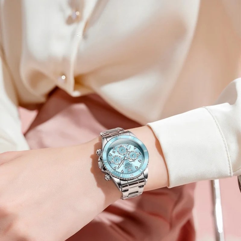 Montre chronographe femme cadran bleu glacier et acier miroir portée par une femme en tailleur blanc et jupe rose